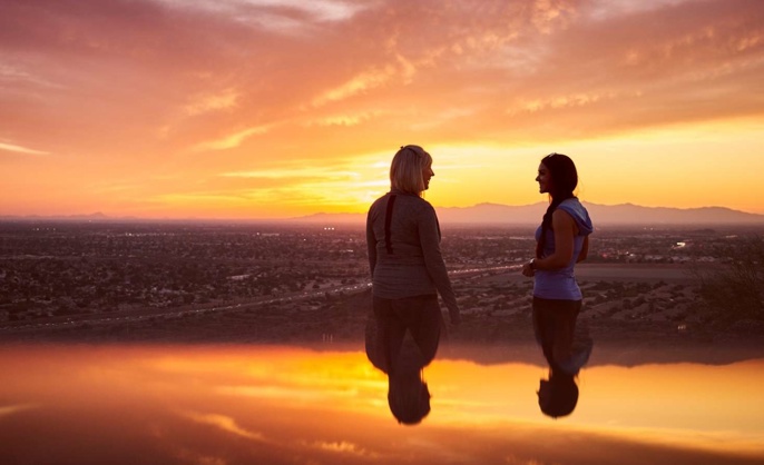 2 people smiling in front of a sunset