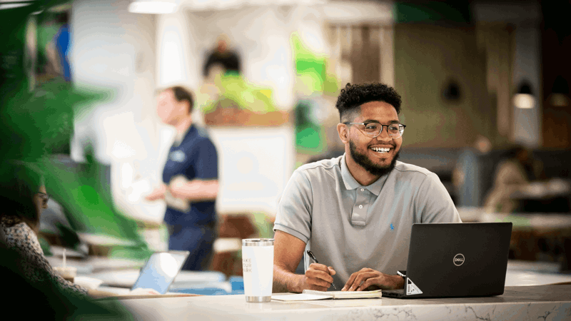 Cox employee working in the cafe with laptop and notepad