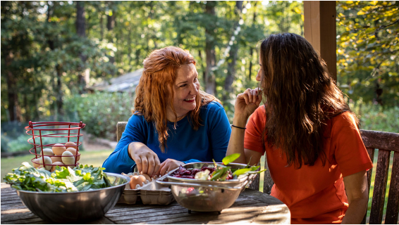 two women sitting at a table with food on it