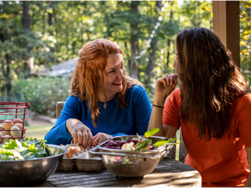 two women sitting at a table with food on it