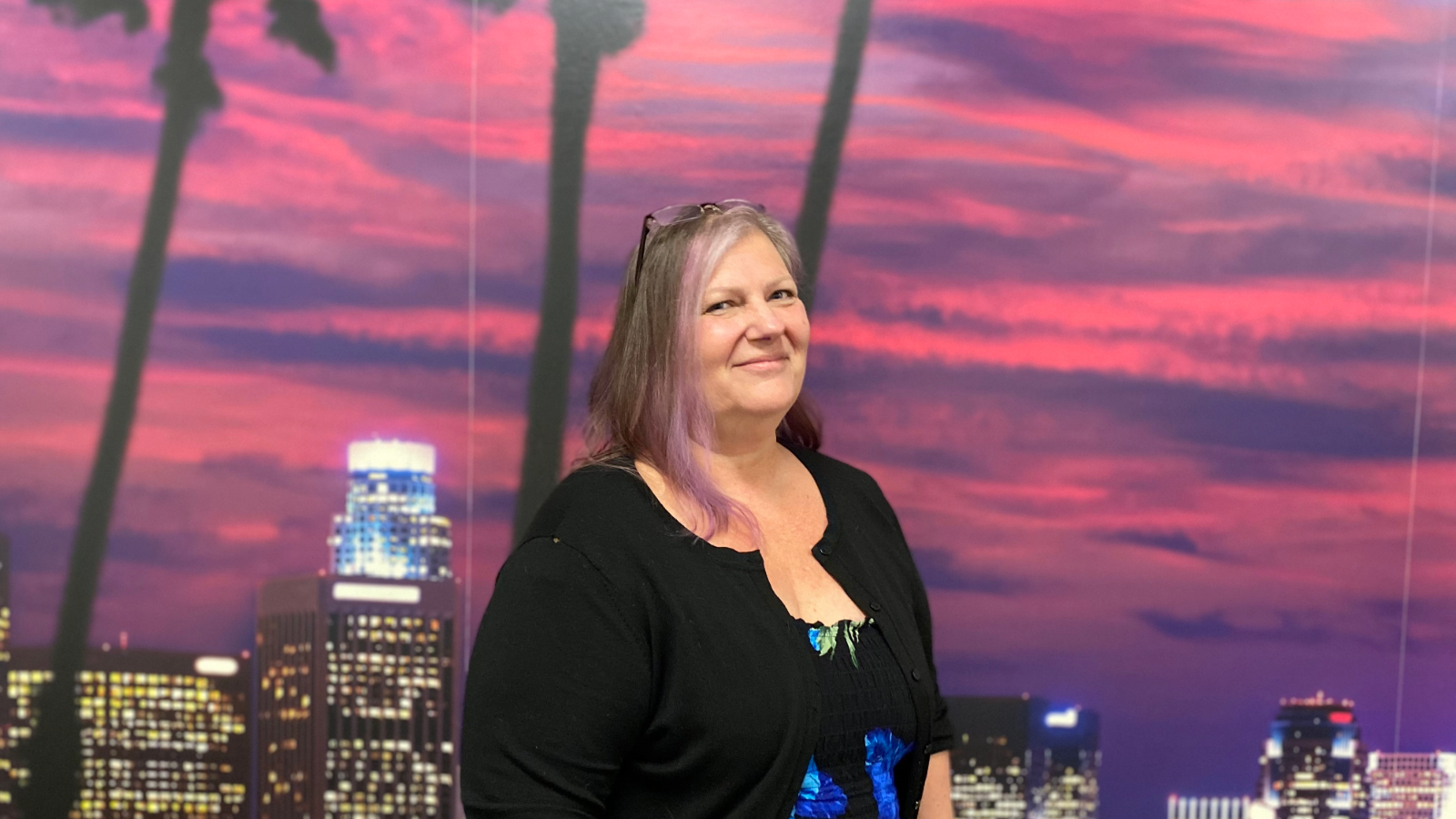 a person smiling in front of a mural