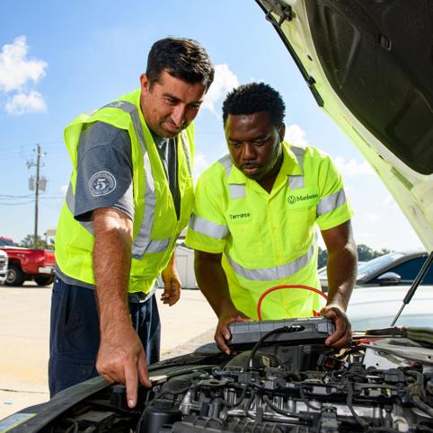 a group of cox automotive employees looking at an open hood of a car