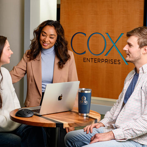 a group of Cox employees sitting at a table with a laptop
