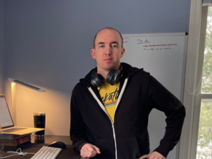 Cox employee posing withheadphones next to a computer