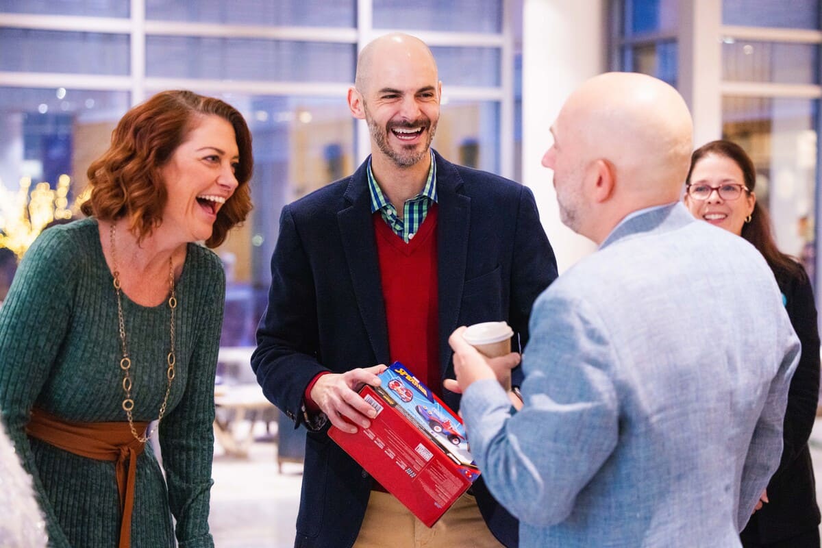a group of people laughing and holding a box