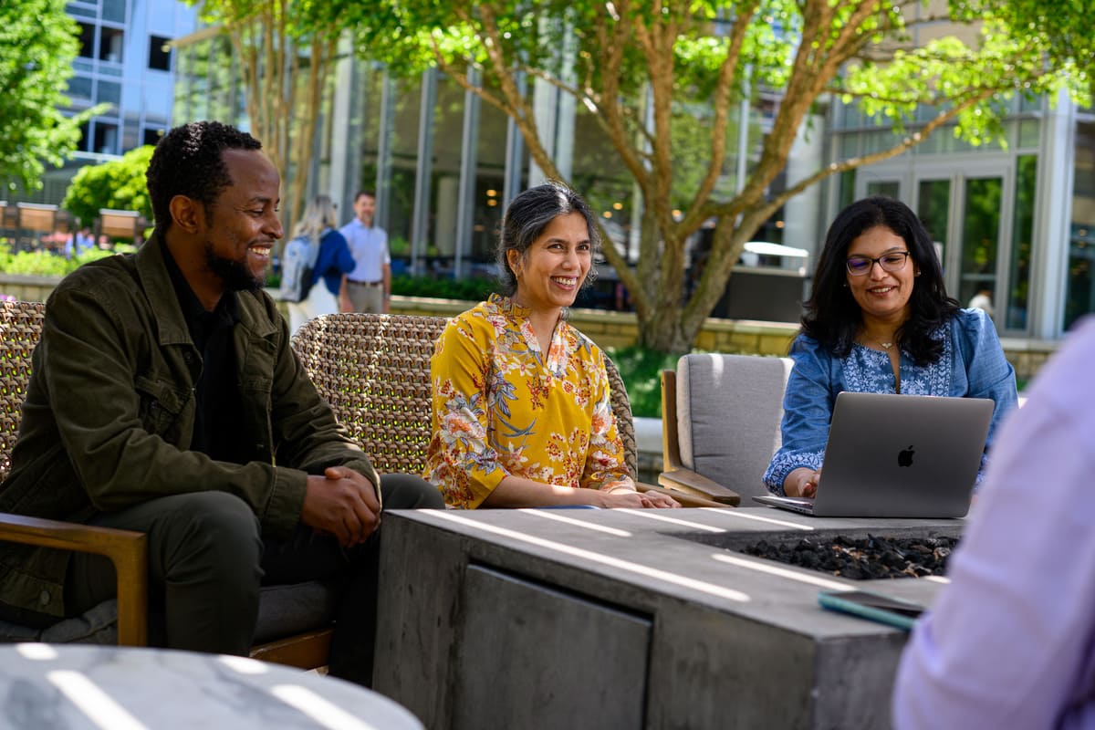 a group of people sitting outside with a laptop