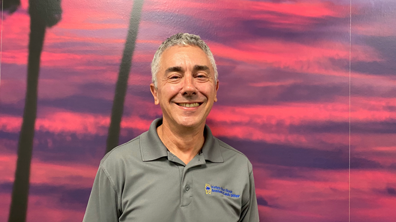a person smiling in front of a pink and purple background