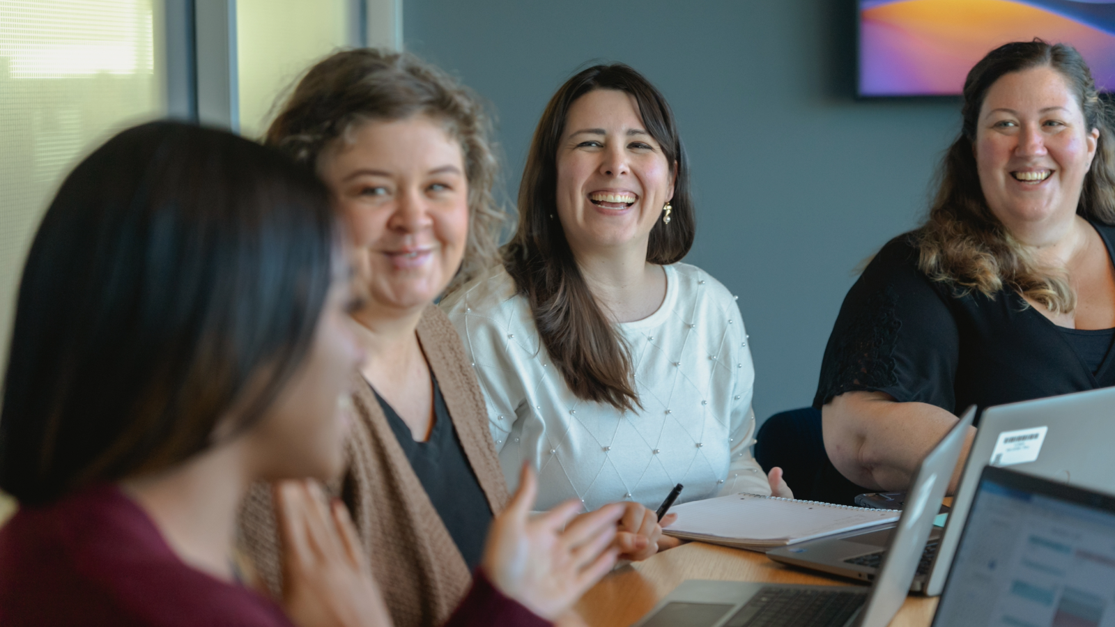 a group of women sitting around a table smiling