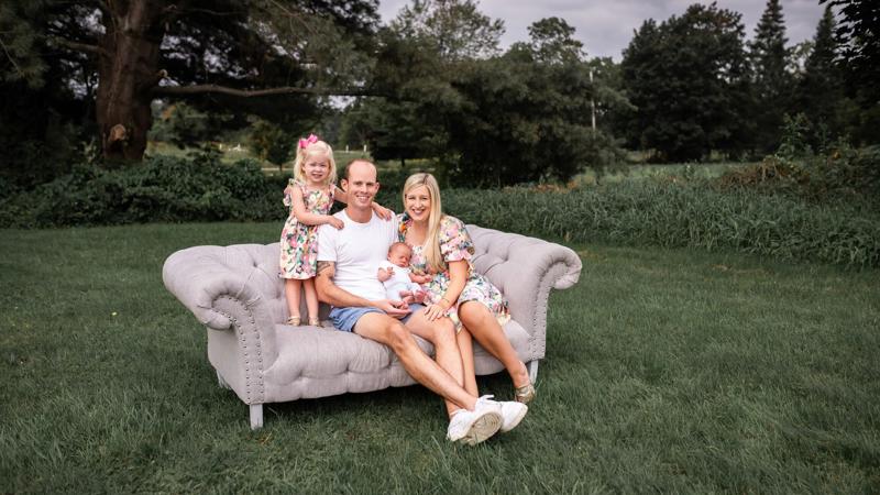 Anthony Jordick posing on his couch with his wife and two kids
