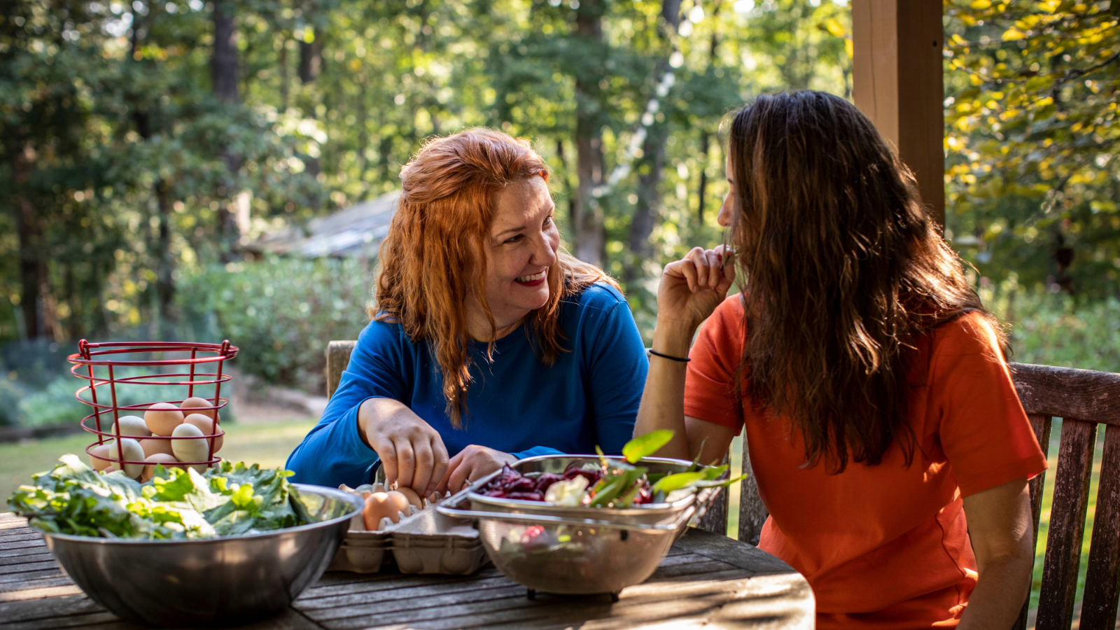 two women sitting at a table with food on it