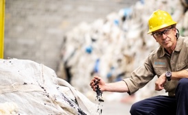 Nexus Circular employee wearing a hard hat and holding a pile of recycled plastics