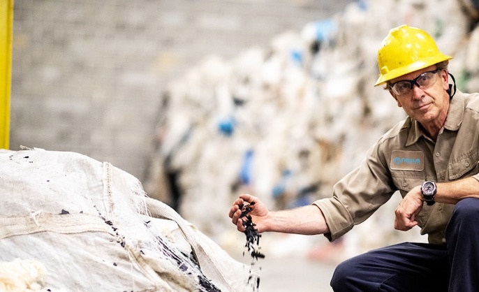 Nexus Circular employee wearing a hard hat and holding a pile of recycled plastics