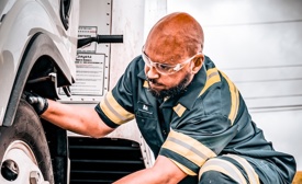 a person wearing safety glasses and working on a truck