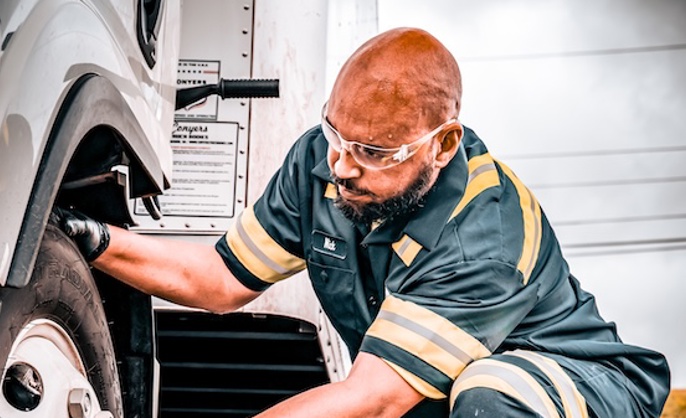 a person wearing safety glasses and working on a truck