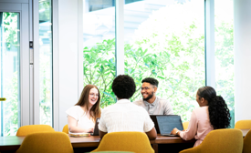 a group of Cox employees sitting around a table with laptops