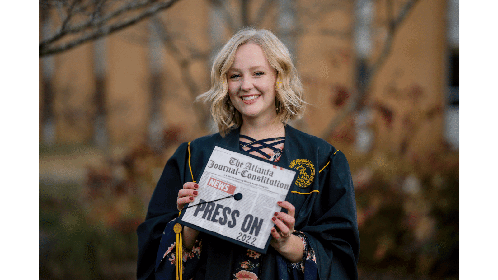 a person in a graduation gown holding a sign