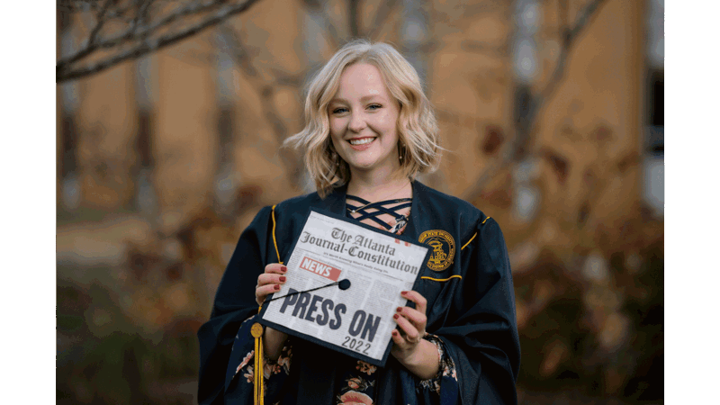 a person in a graduation gown holding a sign
