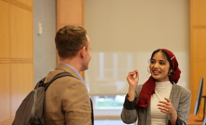 a person in a red scarf talking to a person in a room