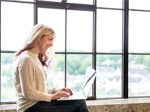 Cox employee working on laptop in front of window