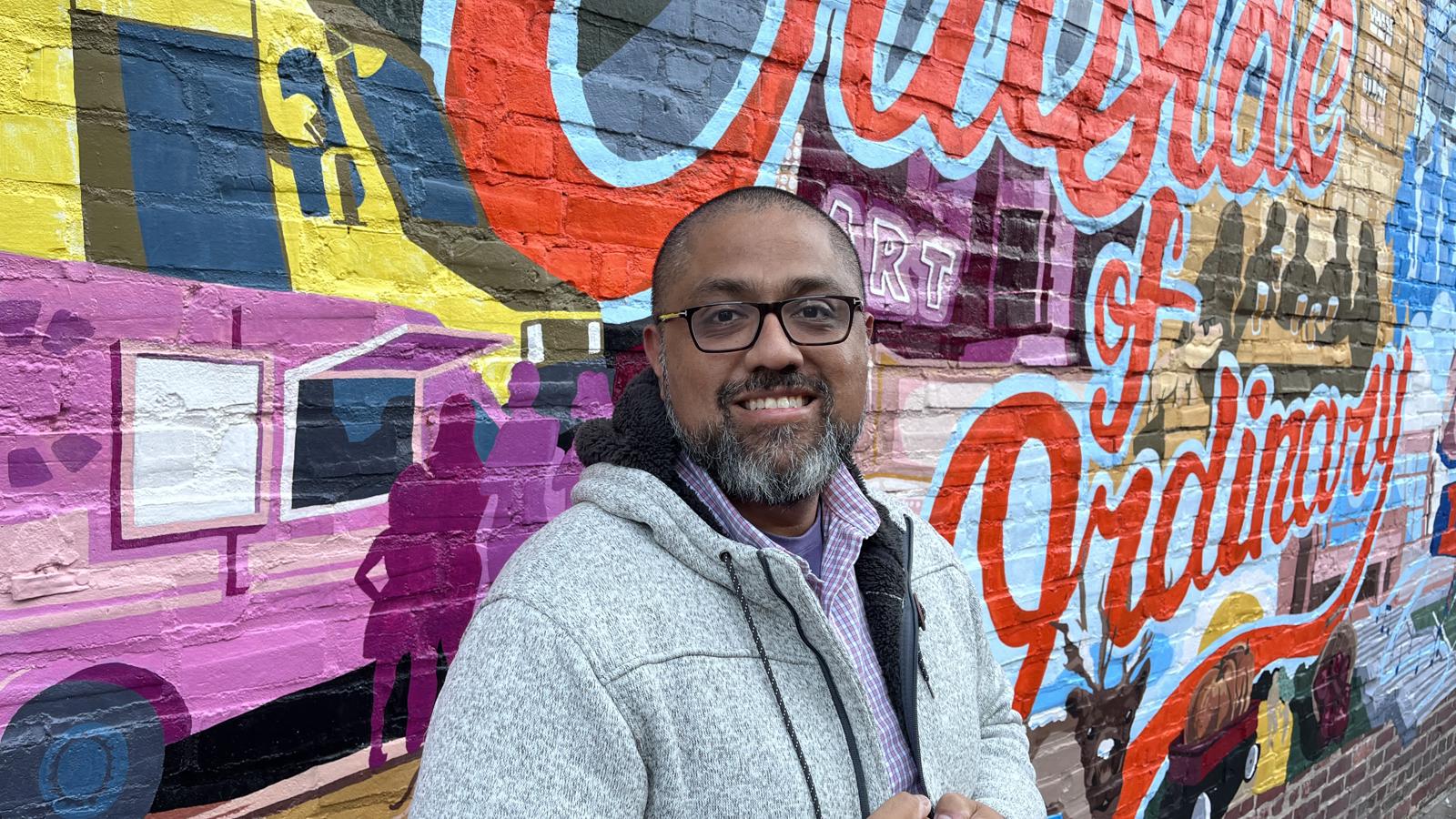 Gustavo Velazque Cox employee headshot in front of mural
