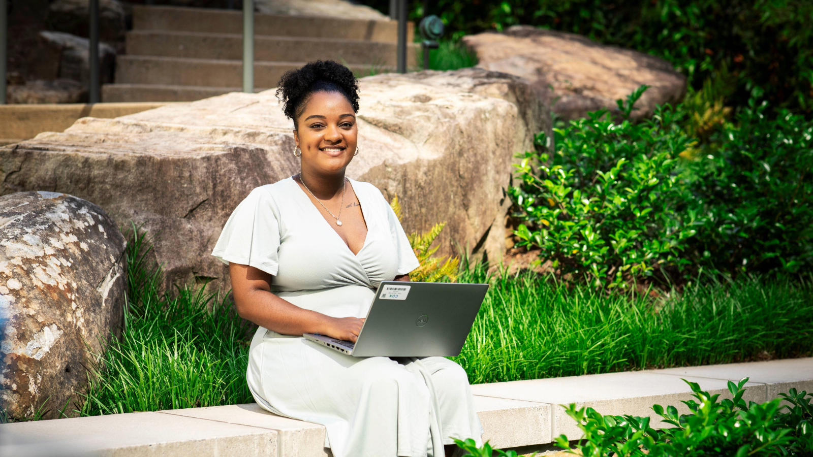 a person sitting on a ledge with a laptop