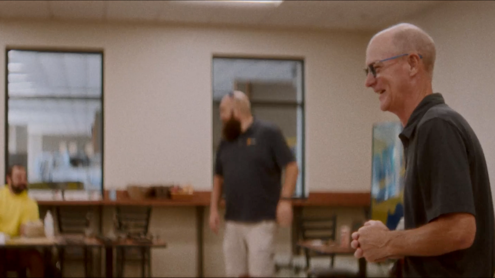 a person in glasses looking at another person in a room