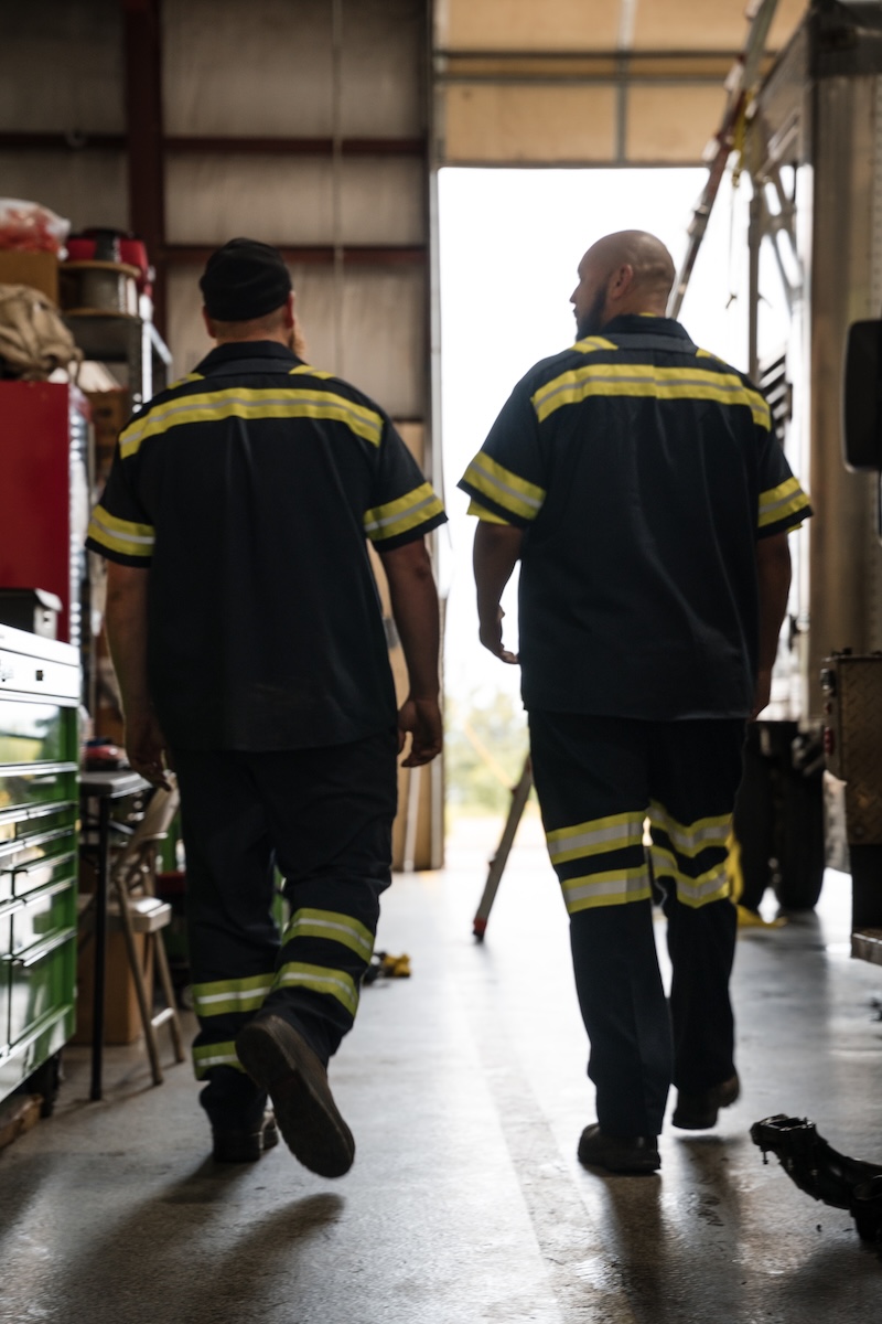two men in uniforms walking in a garage