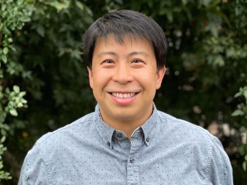 a person smiling in front of bushes