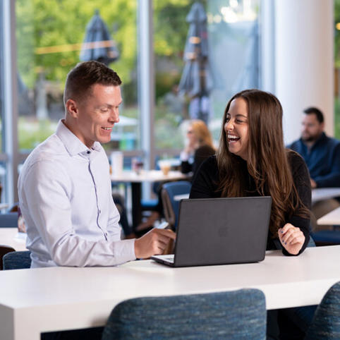 two Cox employees sitting at a table with a laptop